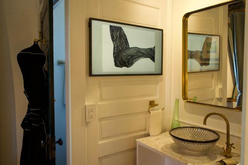 a bathroom with a sink and a door with a mirror at Archaic Outhouse in Santee