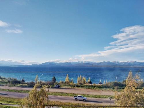 a car driving down a road next to a body of water at Las Victorias Suites Bariloche in San Carlos de Bariloche