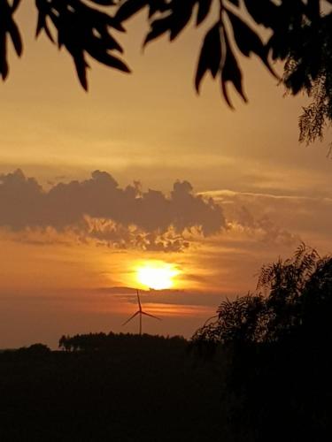 a sunset with a wind turbine in a field at Casinha de férias no campo - Quintinha dos Cavalos - Arruda dos Vinhos in Sabugos