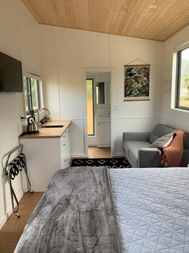 a room with a bed and a couch and a kitchen at Blackball Tinyhouses in Blackball