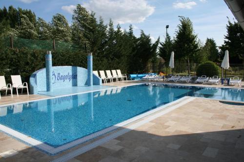 a large swimming pool with chairs and umbrellas at Bagolyvár Inárcs in Inárcs