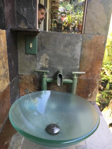 a sink in a bathroom with a man in the mirror at Holualoa bungalows in Kailua-Kona