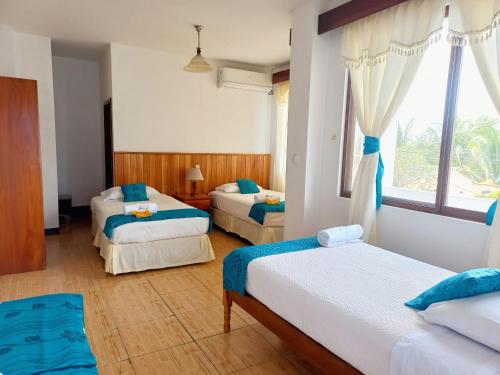 1 dormitorio con 2 camas y ventana en Hotel Sula Sula, en Puerto Villamil