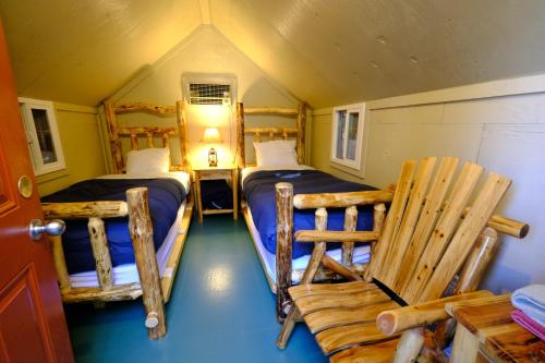 a small room with two beds and a chair at Yosemite Bug Rustic Mountain Resort in Midpines