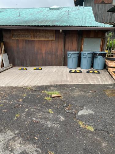 a parking lot with four trash cans in front of a garage at Holualoa bungalows in Kailua-Kona