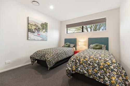 sypialnia z 2 łóżkami i oknem w obiekcie Luxe Arrowtown Home w mieście Arrowtown