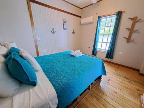 Schlafzimmer mit einem Bett mit blauer Bettwäsche und einem Fenster in der Unterkunft The Odyssey Resort Utila in Utila
