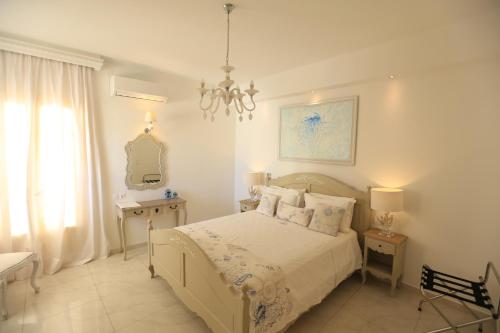 a white bedroom with a bed and a chandelier at The White Suites in Adamas