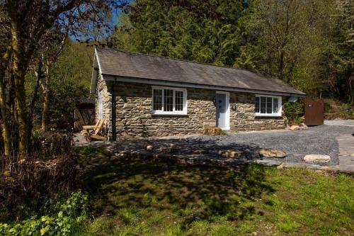 a small stone house in the middle of a yard at Luxurious Riverside Cottage in Snowdonia National Park in Tanygrisiau