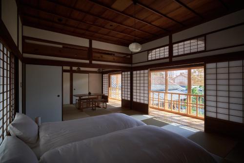 1 dormitorio con cama, mesa y ventanas en 滔々 倉敷民藝館南の宿 toutou, Mingeikan Minami no Yado, en Kurashiki