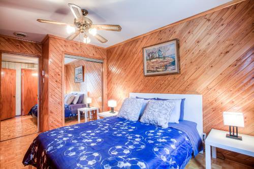 um quarto com uma cama azul e paredes de madeira em Maison chaleureuse a 15 minutes DT Montréal em Montreal