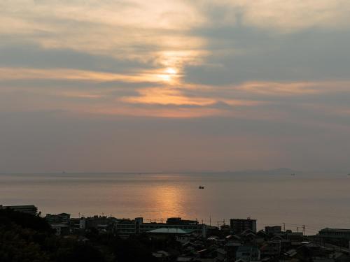 a view of the ocean with the sun setting over a city at KAMENOI HOTEL Awajishima in Awaji