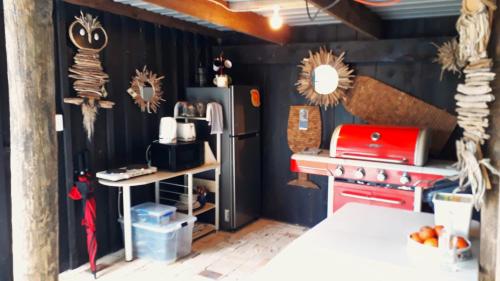 a kitchen with a red stove and a refrigerator at Quirky Woods - Glamping Cabins at Maketu in Maketu
