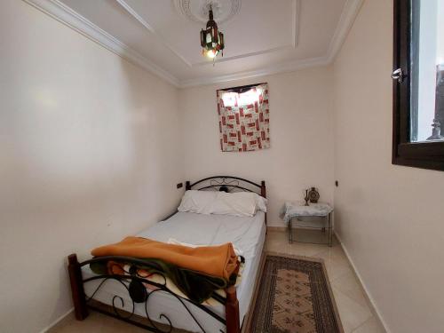 um pequeno quarto com uma cama e uma janela em Samsat House Apartment Taghazout em Taghazout
