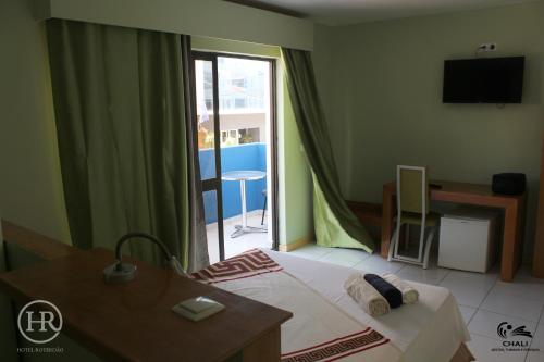 1 dormitorio con cama, mesa y ventana en Hotel Roterdão "Under New Management" en Praia
