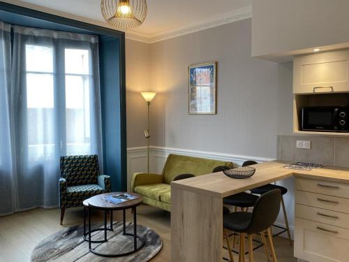 une cuisine et un salon avec un canapé et une table dans l'établissement Appartement Équipé au Cœur de Vichy – Confort et Praticité - FR-1-489-366, à Vichy
