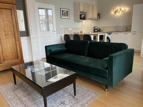 un salon avec un canapé vert et une table dans l'établissement Appartement Équipé avec Balcon au Cœur de Vichy - Proche Thermes et Commerces - FR-1-489-362, à Vichy