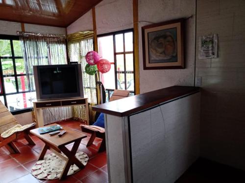 a living room with a television and a table and chairs at Posada Lu.Lu in Choachí