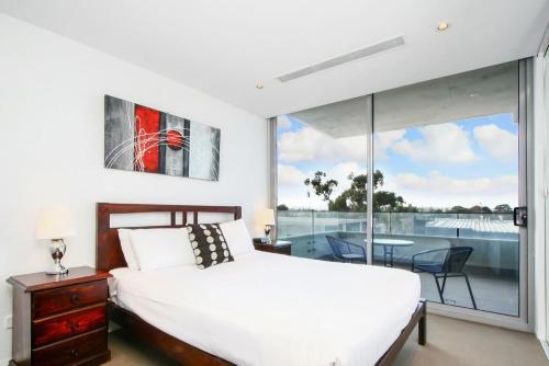 a bedroom with a bed and a balcony with a table at Realm Park Barton ACT in Canberra