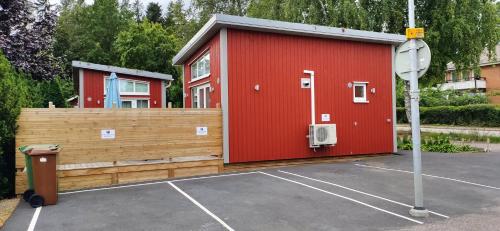 a red building in a parking lot with a fence at Bålsta Studio Houses in Bålsta