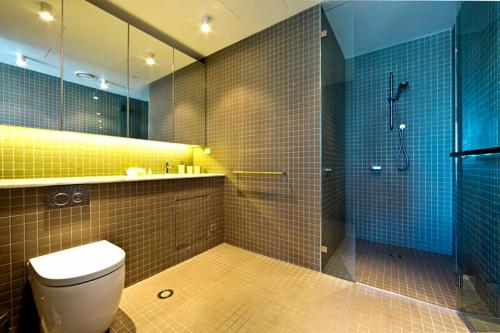 y baño con aseo y ducha con azulejos azules. en Aurora 14, en Canberra