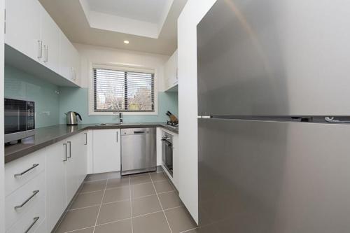 a kitchen with white cabinets and a stainless steel refrigerator at Domain 8 Deakin ACT in Canberra