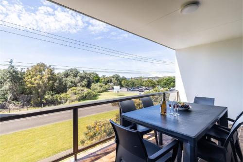 a dining room with a table and chairs and a large window at The Dunes15 fabulous unit with pool tennis court and across the road to the beach in Fingal Bay