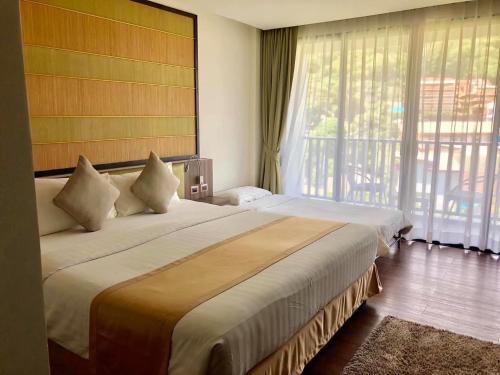 um quarto de hotel com duas camas e uma grande janela em The Beach by Glitter House em Praia de Kata