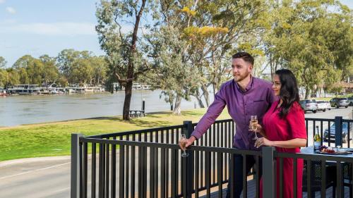 a man and woman standing next to a fence holding wine glasses at Berri Hotel in Berri