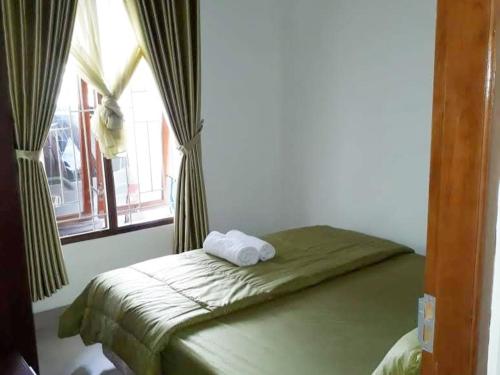 een bed in een kamer met een raam met handdoeken erop bij Omahkoe Jongke in Sleman