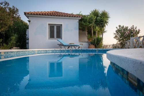 a villa with a swimming pool in front of a house at Beautiful house located on a hill, with a spectacular sea view in Koumeika