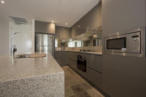 a large kitchen with a sink and a microwave at Manhattan 303 Canberra City ACT in Canberra