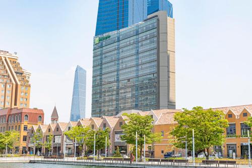a city with tall buildings and a river and trees at Holiday Inn Incheon Songdo by IHG in Incheon