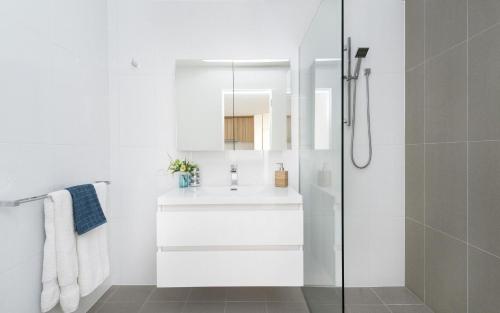 a white bathroom with a sink and a shower at Azure 30 in Kingston 