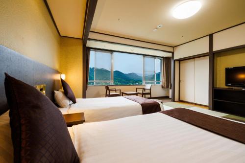 a hotel room with two beds and a television at KAMENOI HOTEL Nagatoro Yorii in Yorii