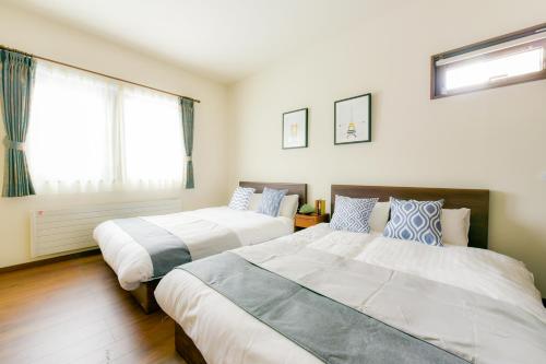 sypialnia z 2 łóżkami i oknem w obiekcie Hostel Sapporo Hachijo Bettei w mieście Okadamachō