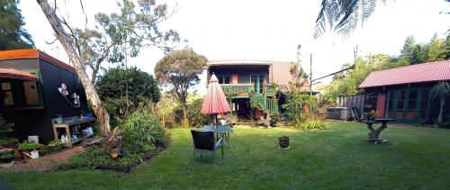 a yard with an umbrella and a house at Quirky Woods - Glamping Cabins at Maketu in Maketu