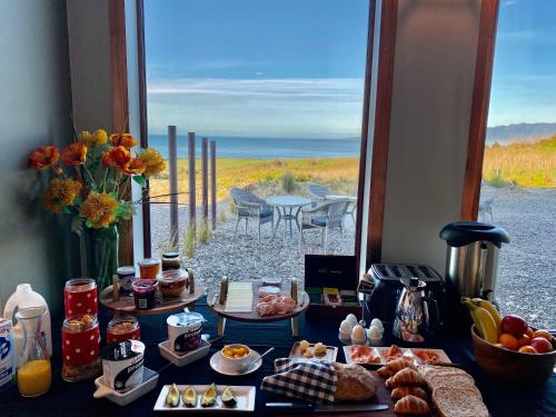 a table with food and a view of the beach at The Cliffs Seaside Lodge in Tuatapere