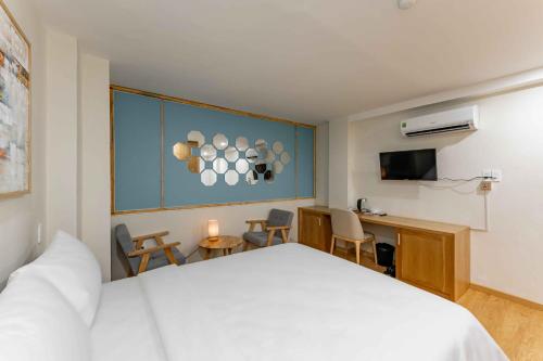 a hotel room with a white bed and a desk at Edoya hotel Dong Khoi in Ho Chi Minh City