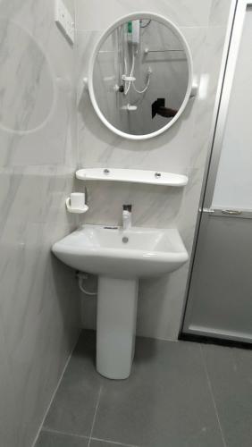 a bathroom with a white sink and a mirror at Victory's Gardens in Mannar