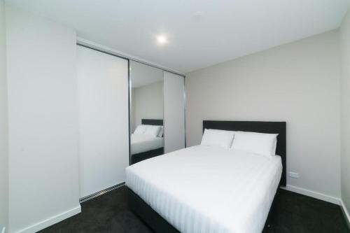 a bedroom with a white bed and a large mirror at Accommodate Canberra - Indigo in Kingston 