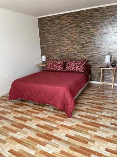 a bedroom with a red bed and a brick wall at Hotel Pacífic Suites Tocopilla in Tocopilla
