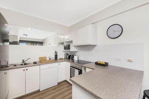 a kitchen with white cabinets and a clock on the wall at The Summit E2 Kingston ACT in Kingston 
