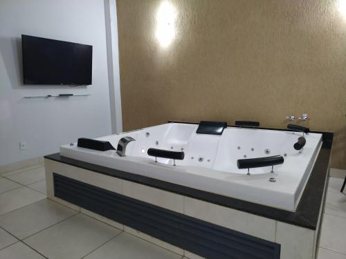 a large bath tub in a room with a tv at Casa com 2 quartos e banheira de Hidromassagem in Trindade