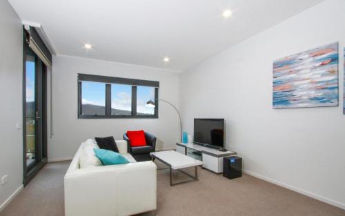 a living room with a white couch and a tv at IQ Smart Apartments 507 Braddon ACT in Canberra