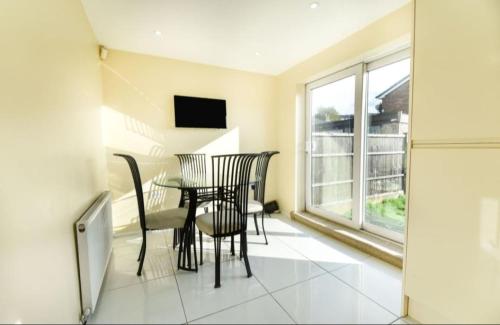a dining room with a table and chairs and a window at 3 bed House Lovely & Modern in Whitefield