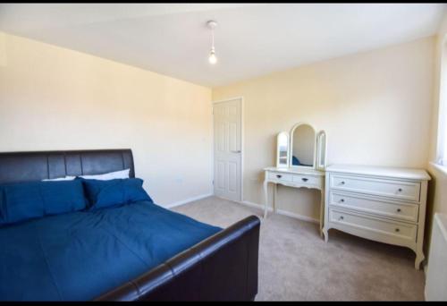 a bedroom with a bed and a dresser and a mirror at 3 bed House Lovely & Modern in Whitefield