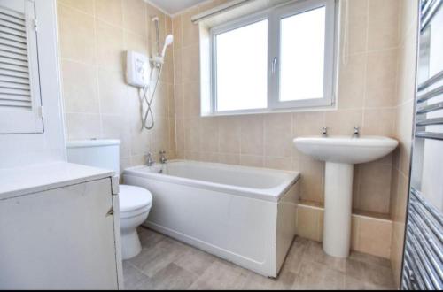 a bathroom with a white tub and a sink and a toilet at 3 bed House Lovely & Modern in Whitefield