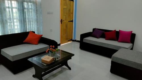 a living room with two couches and a coffee table at Victory's Gardens in Mannar