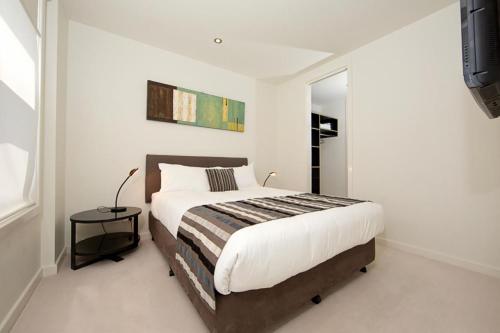 1 dormitorio con 1 cama grande y espejo en Trieste Apartments Kingston ACT, en Canberra